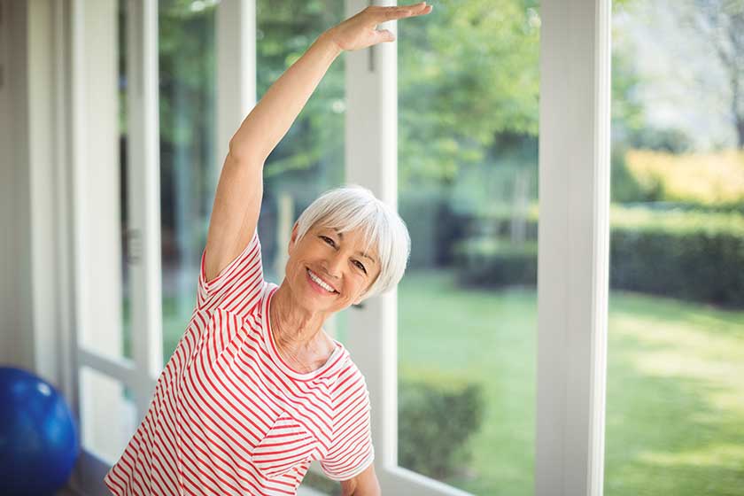 Portrait of senior woman performing stretching exercise at home