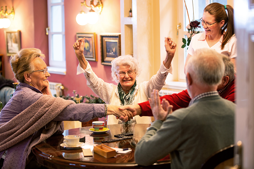 Retirement home occupants sitting at the table together and playing various games