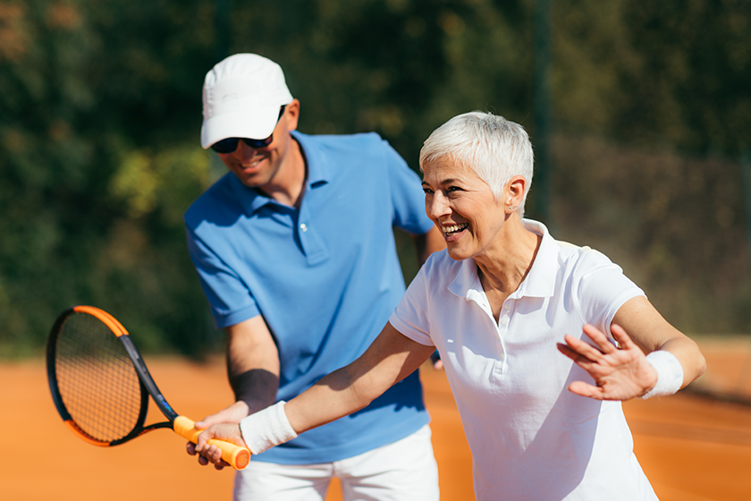 Tennis instructor with senior woman, tennis training lesson 